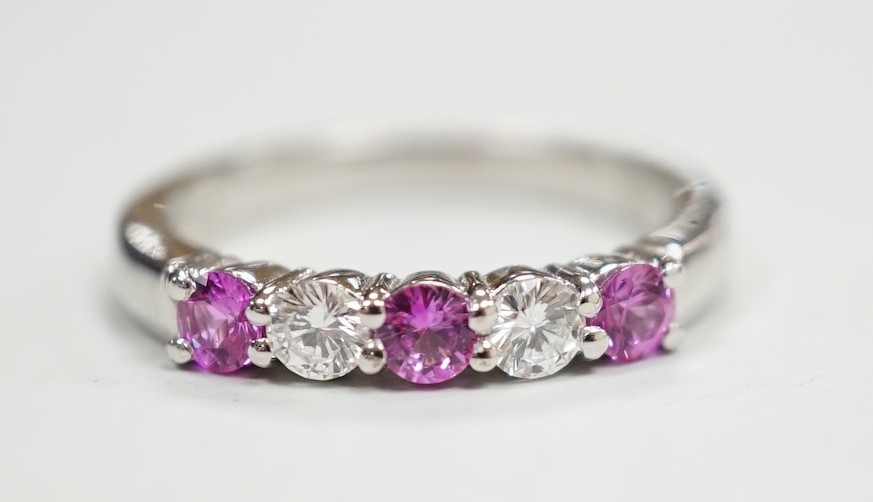 A modern 18ct white gold, three pink stone and two stone diamond set half hoop ring, size M, gross weight 4 grams.